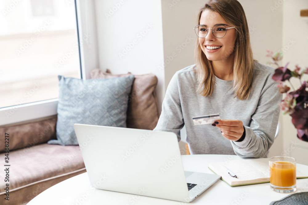 Photo of smiling woman using laptop while holding credit card Photo of smiling woman using laptop while holding credit card