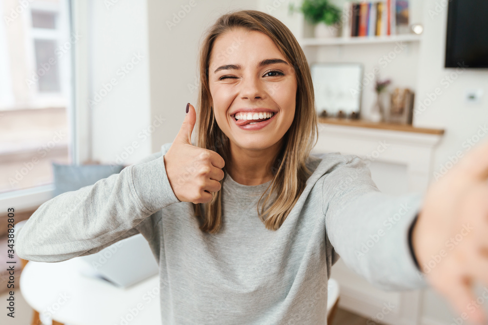 Photo of woman showing thumb up and winking while taking selfie Photo of woman showing thumb up and winking while taking selfie