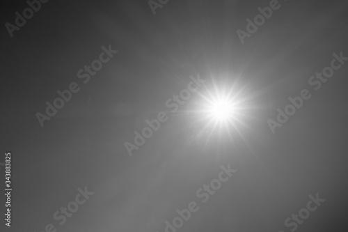 Abstract nature background of bright sunlight, sunbeam, sun rays with lens flares on sunny dark sky horizon for black & white or monochrome texture wallpaper, power & solar energy concept, free space