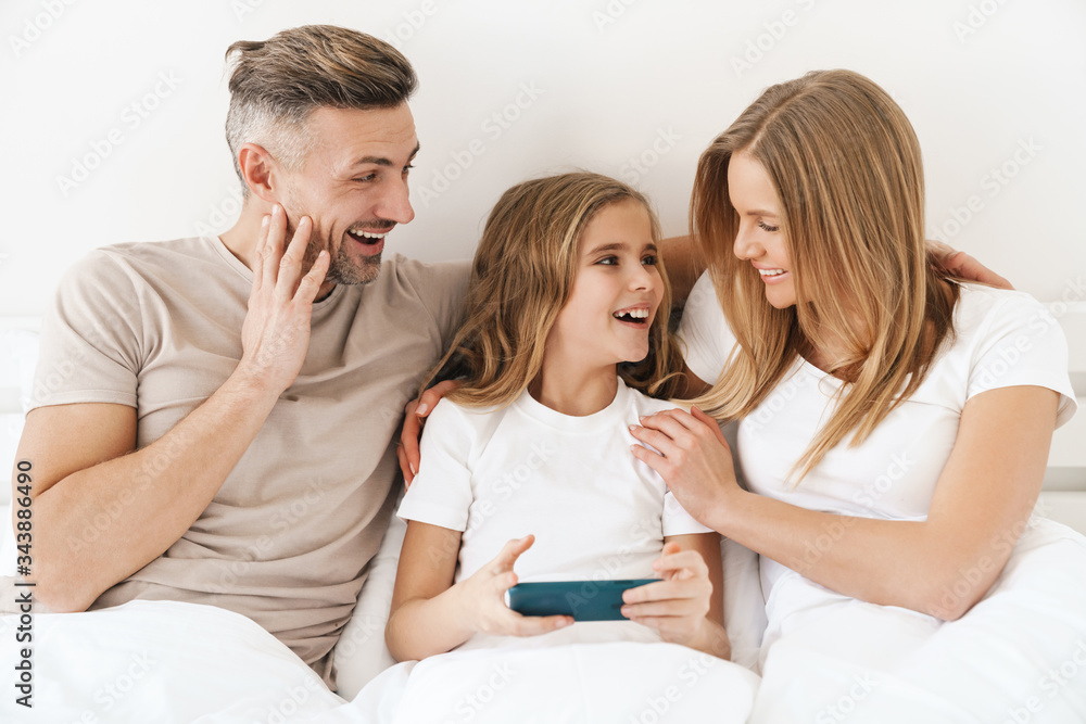 Photo of girl playing video game on cellphone with parents in bad