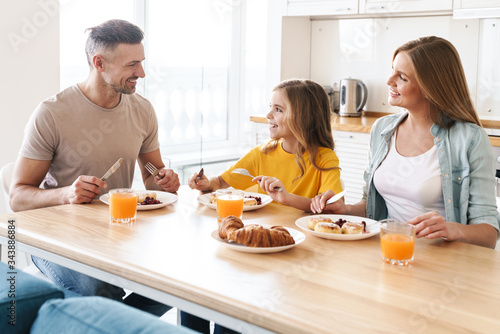 Photo of happy family smiling and talking while having breakfast