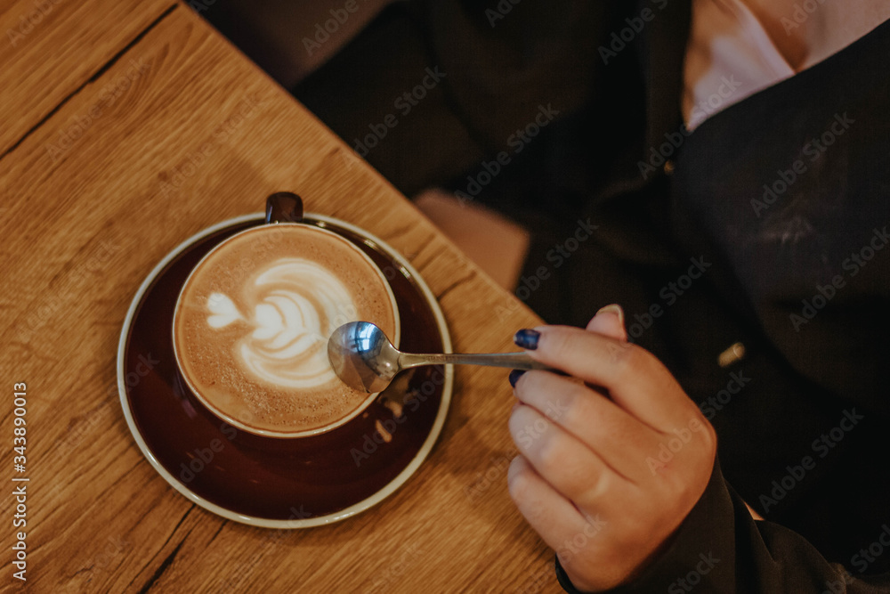 Topviews of hands holding Latte art coffee cup on old wooden table background.