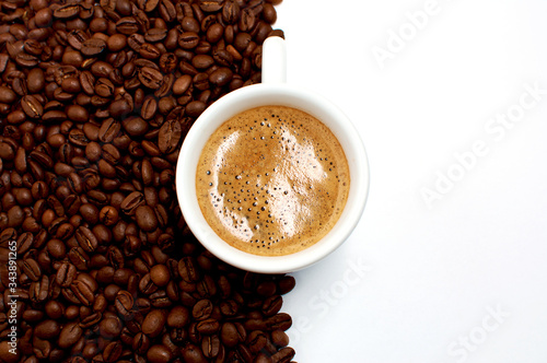 white cup of fresh aromatic coffee and roasted coffee grains on a white background