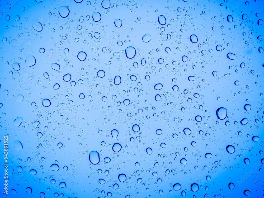 Raindrops on a blue glass, abstract blue background.