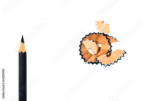 Top view of some pencil shavings placed beside a black color wood pencil