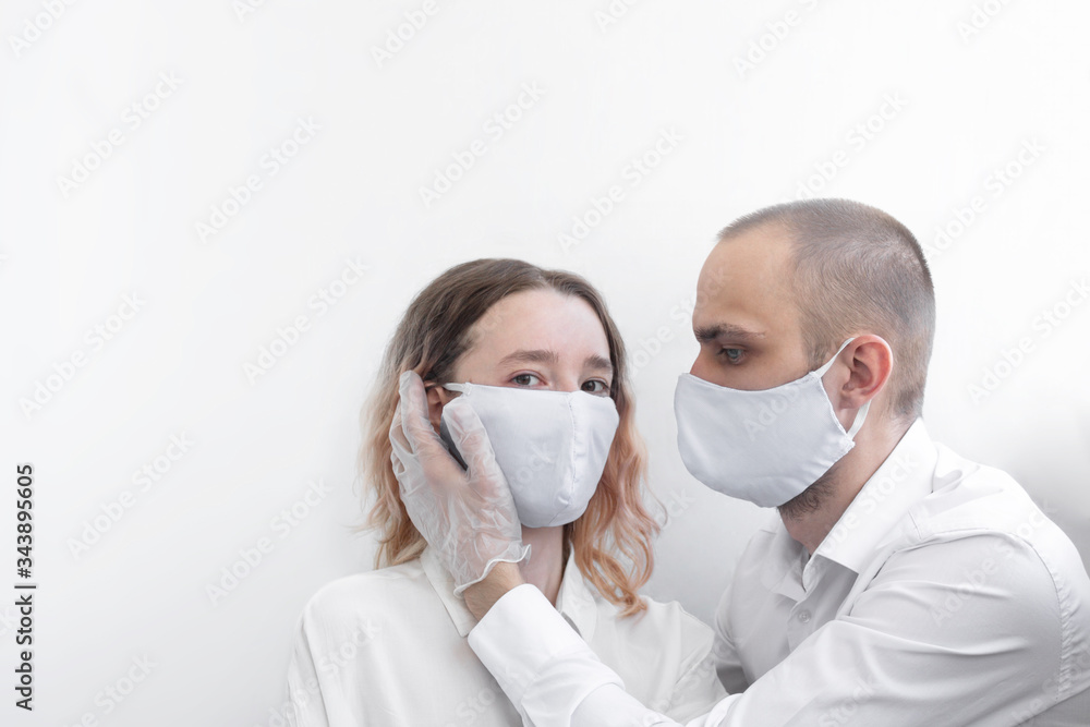 Young couple wearing surgical mask over white background, healthcare and infection control concept. Man and woman in a mask. Selective focus. Young couple wearing surgical mask over white background, healthcare and infection control concept. Man and woman in a mask. Selective focus.