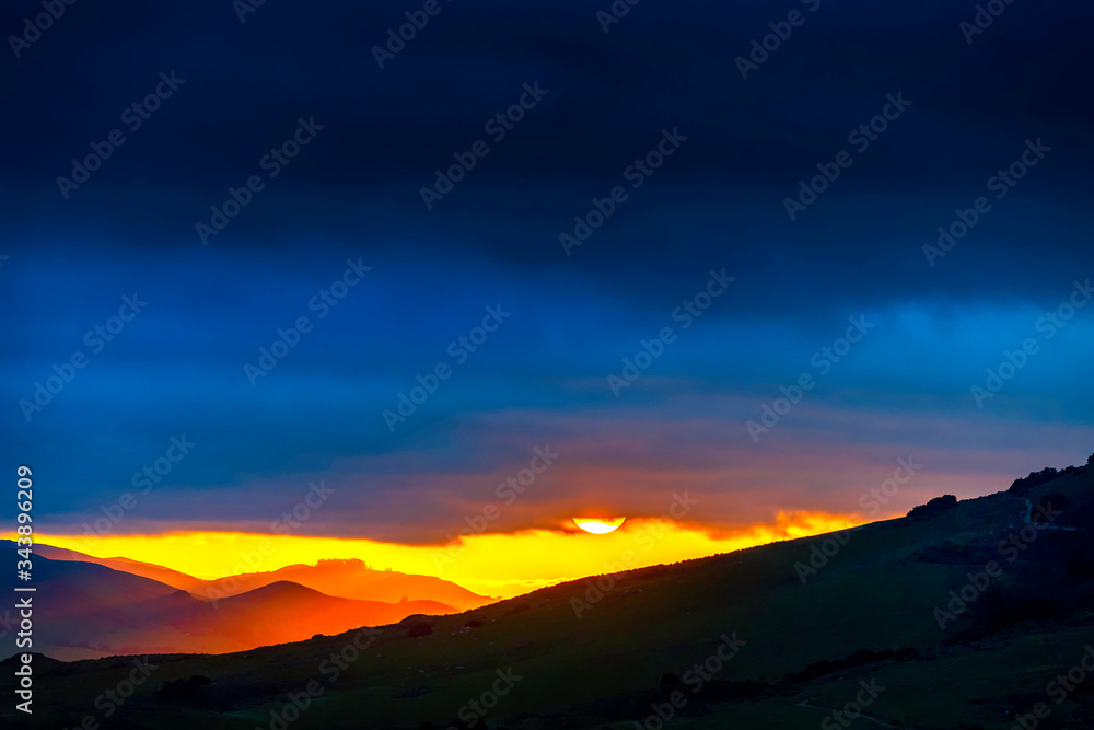 Sun setting over Silhouetted Mountains, Clouds 