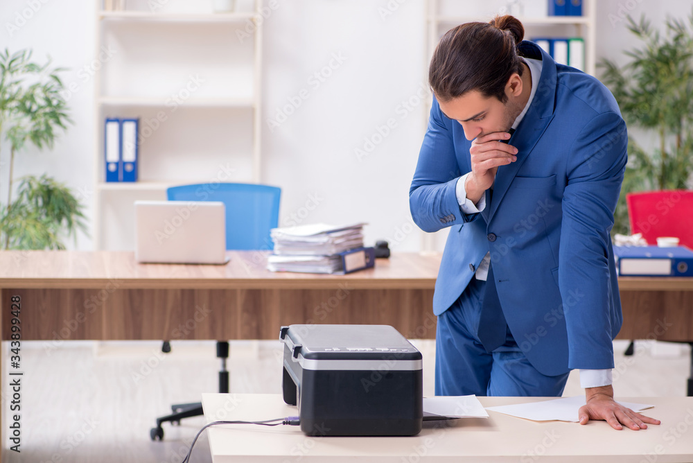 Young male employee making copies at copying machine Young male employee making copies at copying machine
