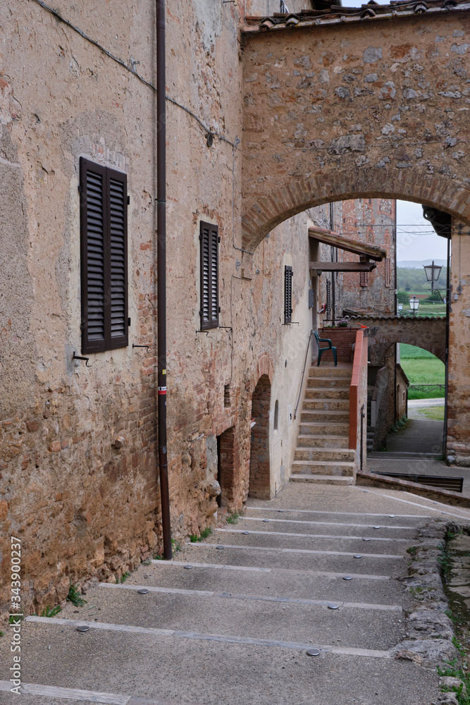 Old houses and staircase in Monteriggioni. Solo Backpacker Trekking on the Via Francigena from Lucca to Siena. Walking between nature, history, churches,