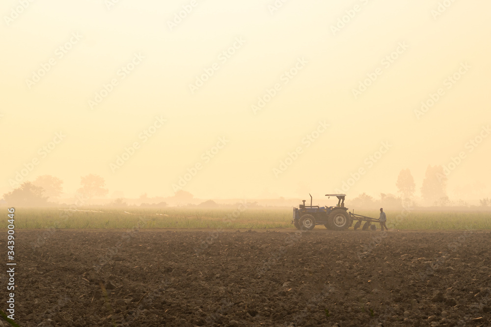 Farmer agriculture tractor asia farm Rice manioc,Asian farmers are driving tractor to adjust the topsoil for planting cassava vegetables, agricultural products