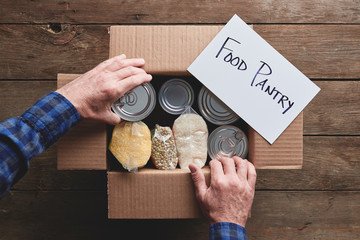 a person packing a donation box with food items for a food pantry delivery