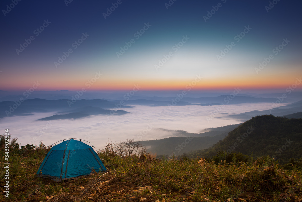 Majestic sunset with Camping tent in the mountains landscape. Overcast sky.