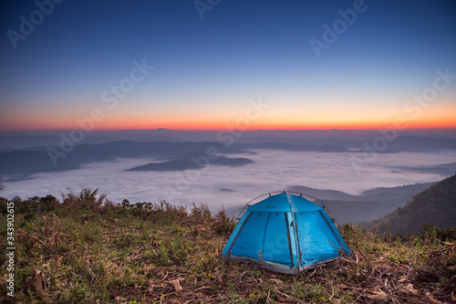 Majestic sunset with Camping tent in the mountains landscape. Overcast sky.