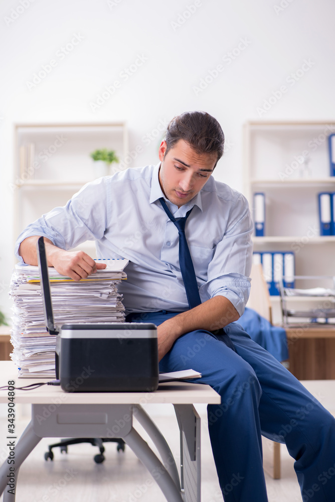 Young male employee making copies at copying machine Young male employee making copies at copying machine
