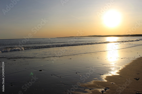 Watery sun on sea and sandy shore