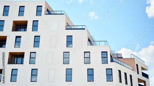 Contemporary residential building exterior in the daylight. Modern apartment buildings on a sunny day with a blue sky. Facade of a modern apartment building © Grand Warszawski