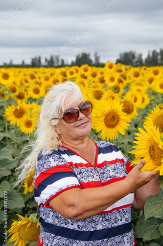 Portrait of an elderly woman in a field of sunflowers.