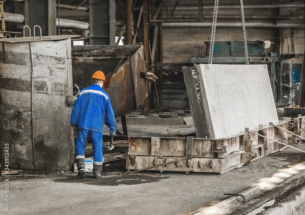 A working man in a reinforcement workshop controls equipment for moving metal and concrete structures A working man in a reinforcement workshop controls equipment for moving metal and concrete structures