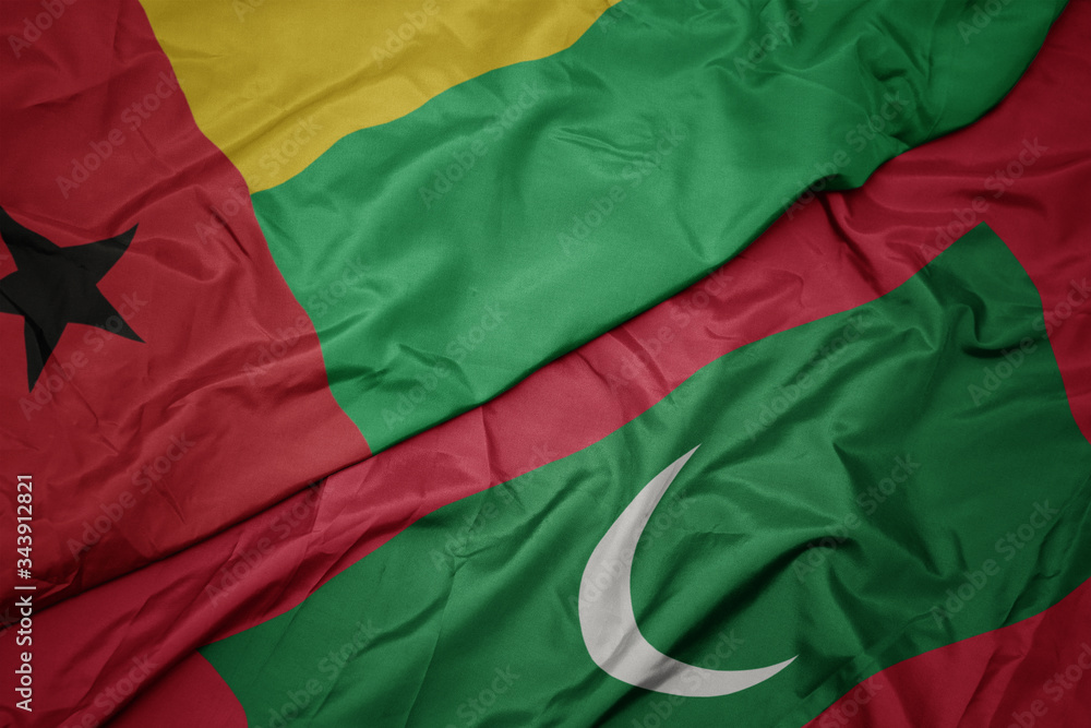 waving colorful flag of maldives and national flag of guinea bissau.