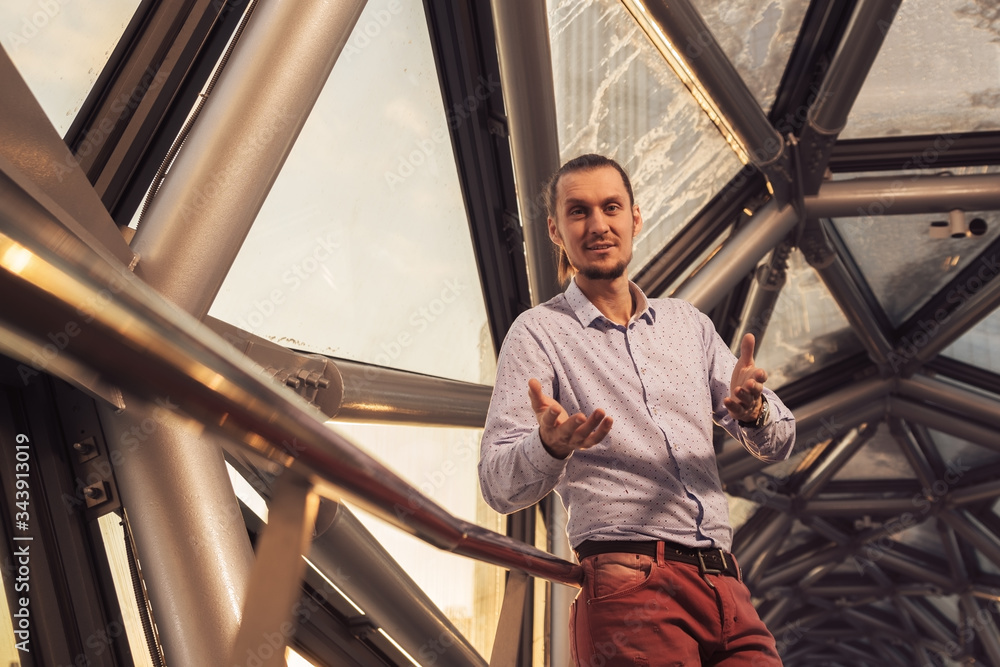 a young businessman explains his project by looking into the frame and gesturing with his hands a young businessman explains his project by looking into the frame and gesturing with his hands