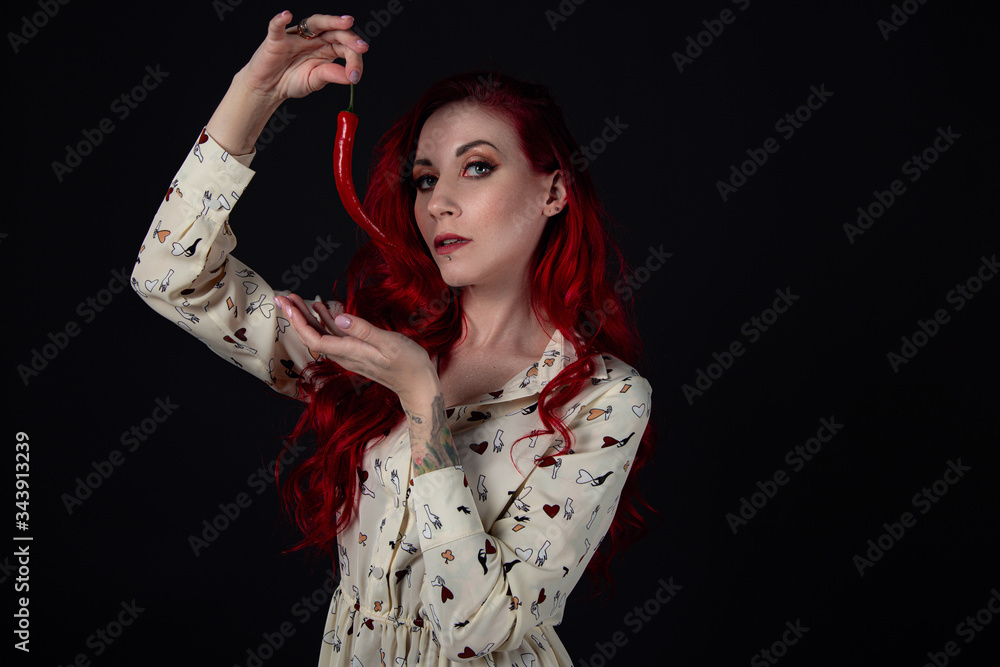 Studio portrait of beautiful young woman with chili pepper Studio portrait of beautiful young woman with chili pepper