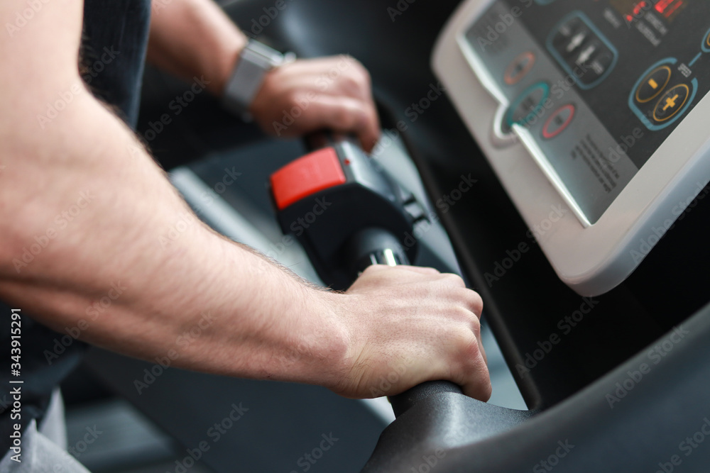 Close-up of hands on a treadmill simulator.
young man holds on to the simulator while walking Close-up of hands on a treadmill simulator.
young man holds on to the simulator while walking