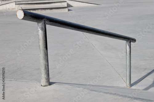 Sloped metal rail for grind tricks in an empty concrete skatepark
