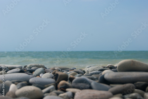 Beach. View of the sea and smooth horizon from the pebble beach. In the foreground are large pebble stones. It's a focus. Background for blog or site, photowallpaper for computer.