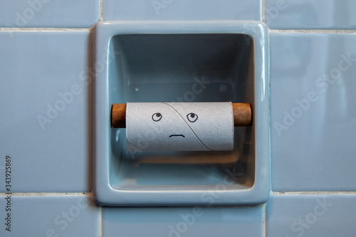 empty roll of toilet paper with sad face in a toilet paper holder
