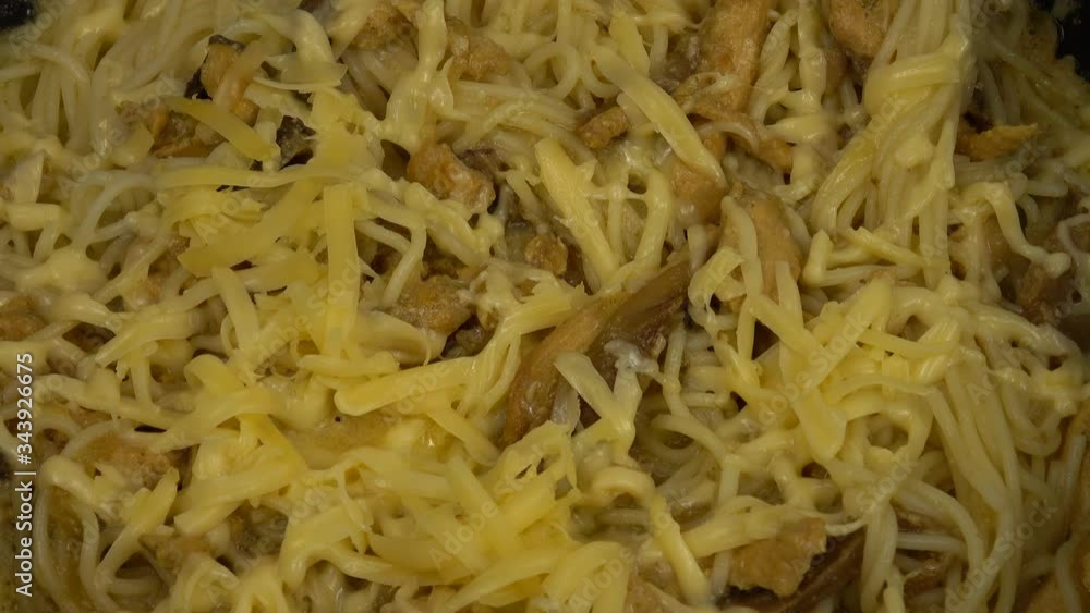 Pasta with chicken and mushrooms in white sauce and cheese over the top in a frying pan. Home cooking Pasta with chicken and mushrooms in white sauce and cheese over the top in a frying pan. Home cooking