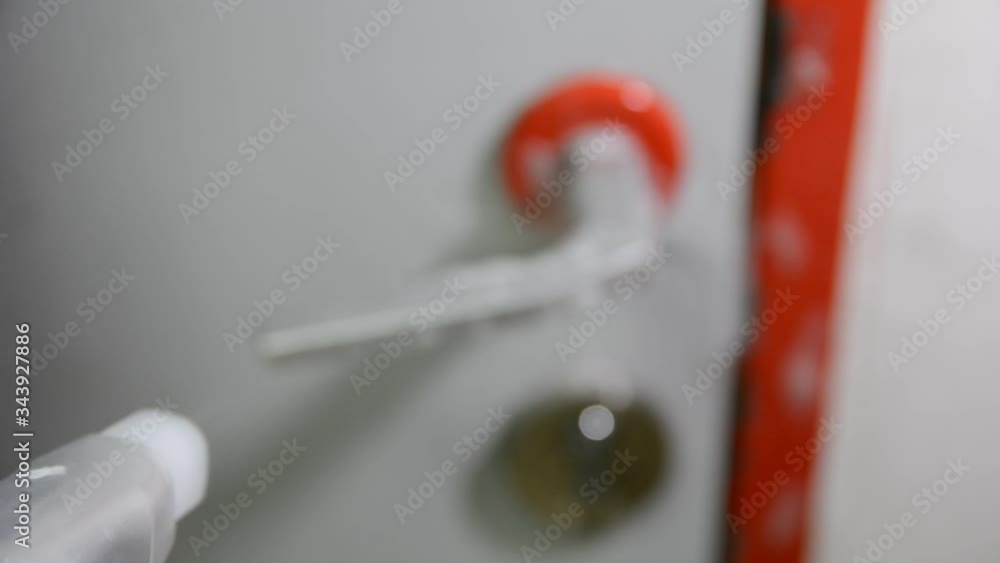 Disinfects the doorknob with spray. This closeup video shows anonymous cleaning hands spraying and scrubbing a dirty door knob to disinfect it. selective focus. Disinfects the doorknob with spray. This closeup video shows anonymous cleaning hands spraying and scrubbing a dirty door knob to disinfect it. selective focus.