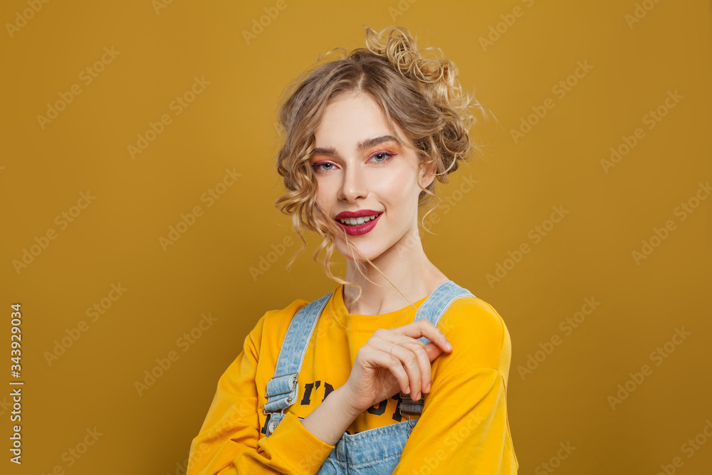 Portrait of pretty girl with long blonde curly hair on bright yellow background Portrait of pretty girl with long blonde curly hair on bright yellow background