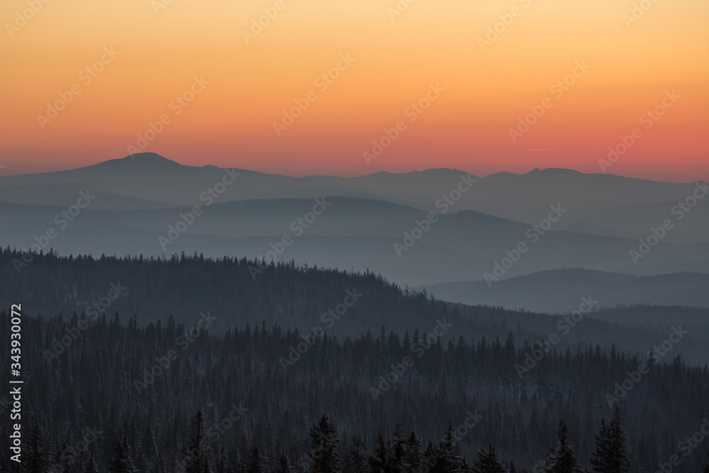 Beautiful smoky sunset in the mountains. The sun sets over the horizon
