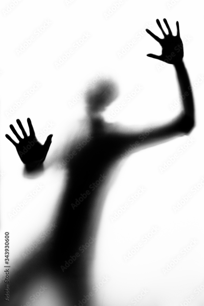 persona in silhouette (b/w) fotografata attraverso un vetro mostra i palmi delle mani