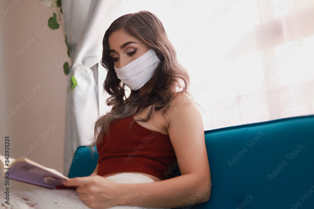 Young woman reading with mask at home due health contingency Young woman reading with mask at home due health contingency