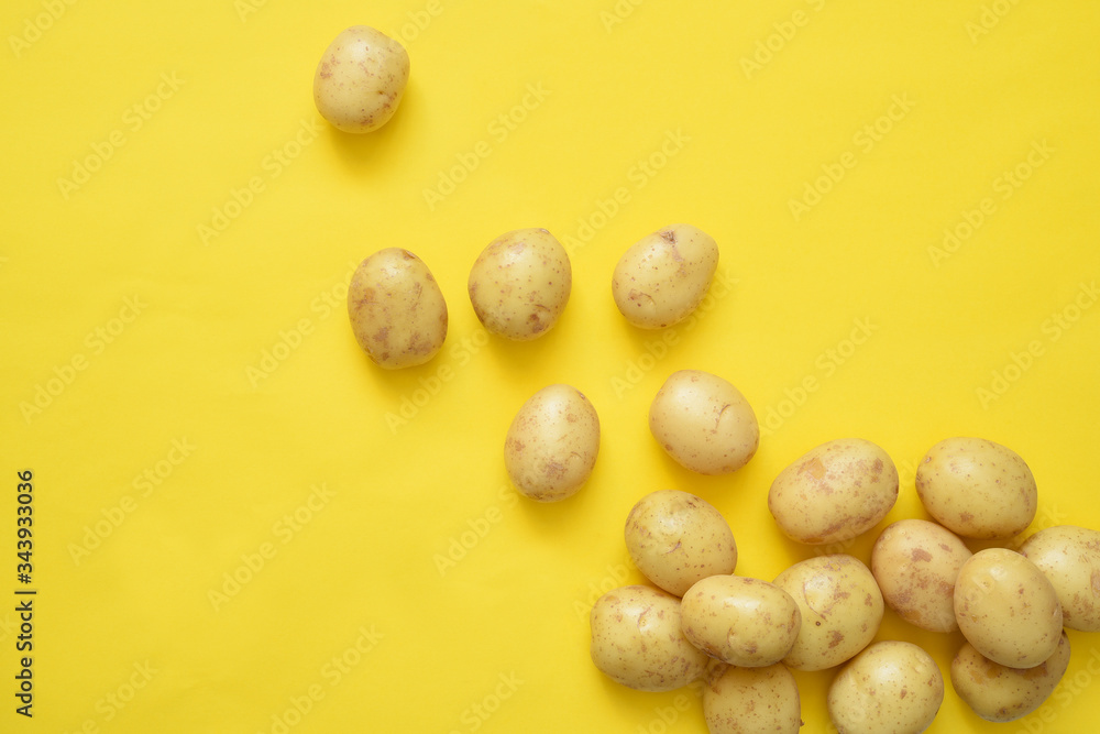 Young fresh potatoes on a yellow background.