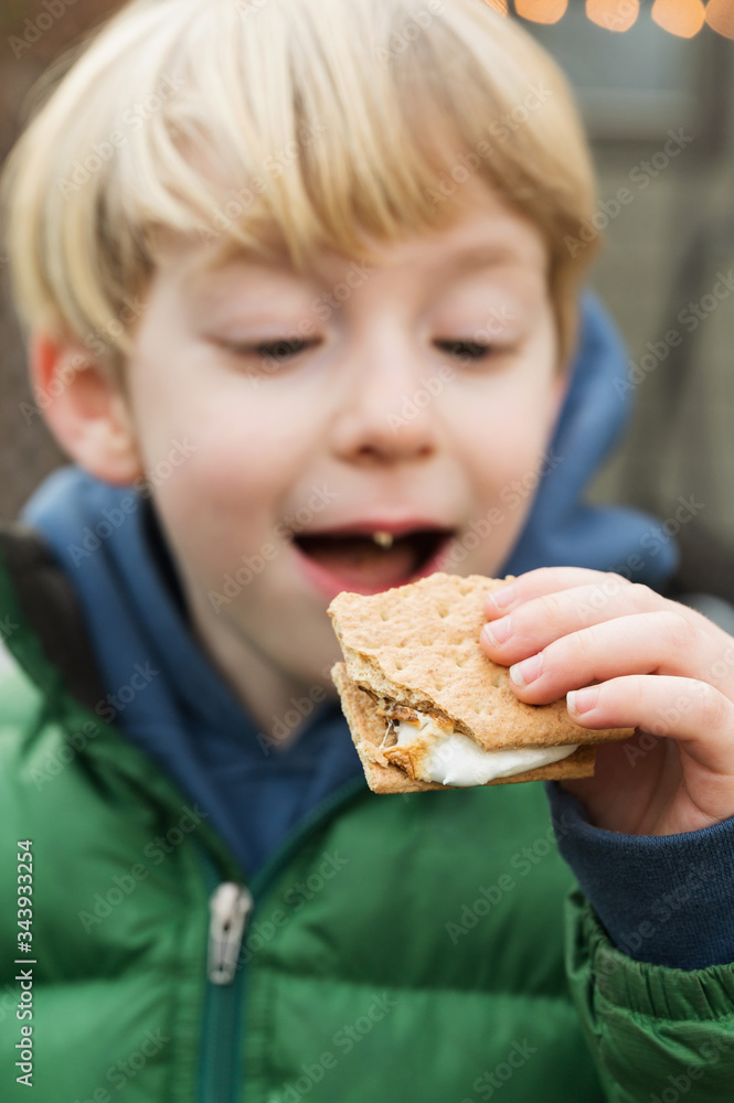 Cute boy (4-5) eating cracker with marshmallow Cute boy (4-5) eating cracker with marshmallow
