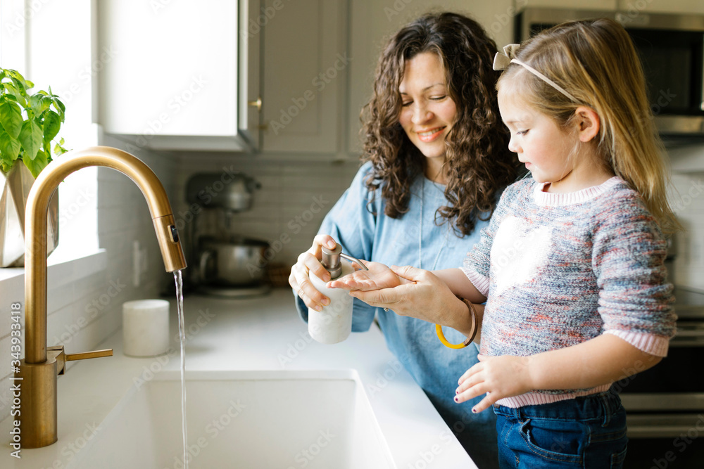 Mother and daughter washing hands in kitchen sink Mother and daughter washing hands in kitchen sink