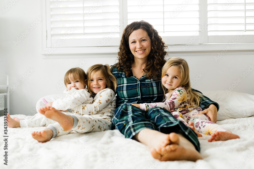 Woman sitting with her daughters on bed Woman sitting with her daughters on bed
