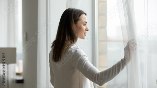 Free Download Young woman open curtains at home or hotel look in window distance thinking or dreaming, happy millennial female admire view, feel optimistic and positive, welcome new sunny day, early morning - GFXLoad