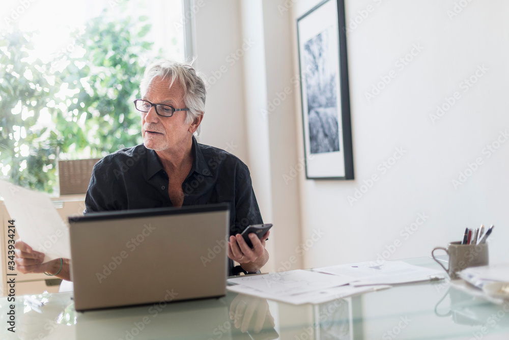 Senior man sitting in home office and using laptop Senior man sitting in home office and using laptop