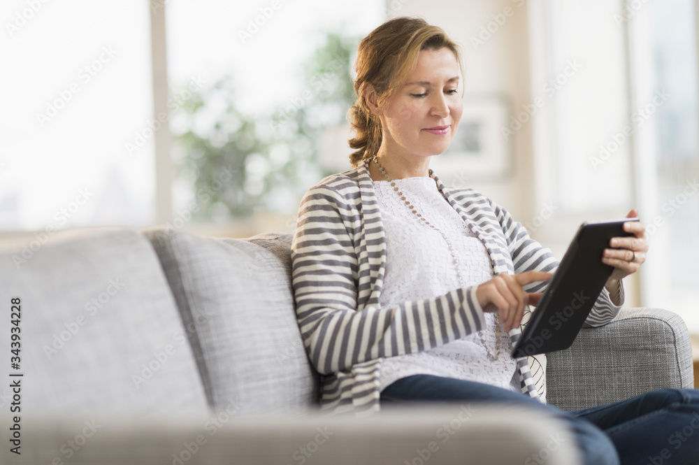 Woman sitting on sofa using tablet pc Woman sitting on sofa using tablet pc