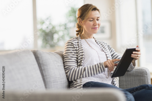 Woman sitting on sofa using tablet pc photo