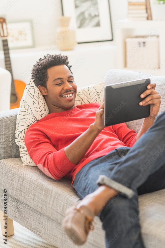 Man lying on sofa and using tablet PC Man lying on sofa and using tablet PC