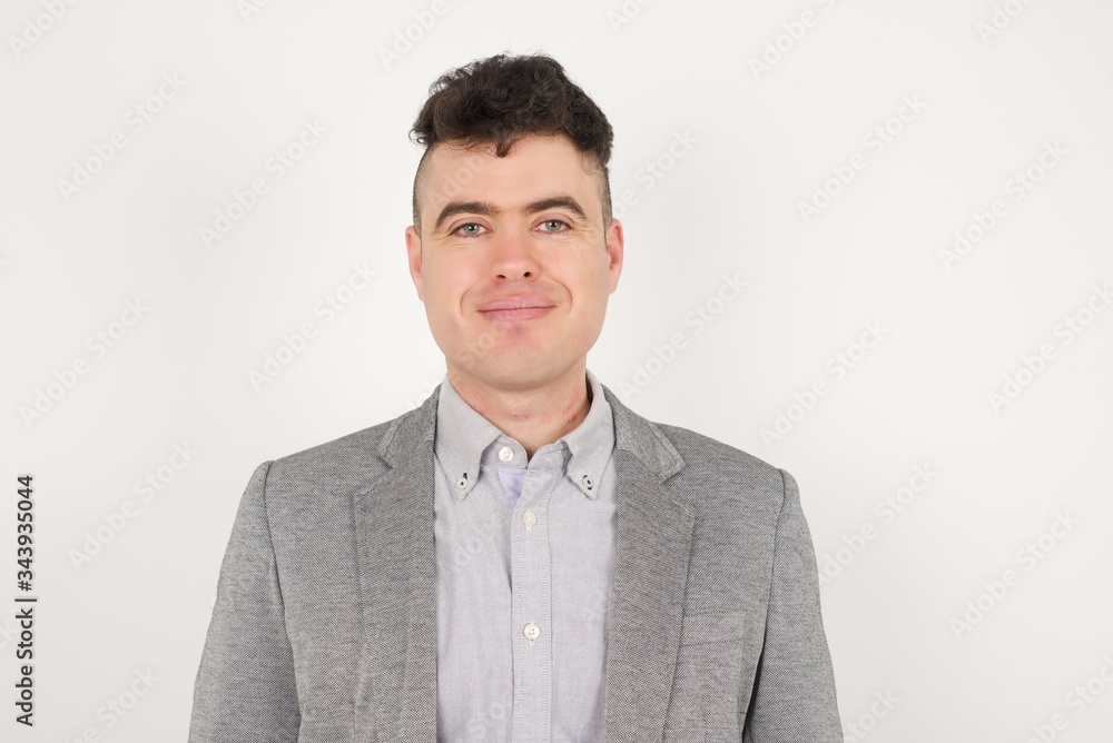 Close up studio shot of handsome young mixed race man model with curly dark hair looking at camera with charming cute smile while posing against white blank copy space wall for your content Close up studio shot of handsome young mixed race man model with curly dark hair looking at camera with charming cute smile while posing against white blank copy space wall for your content