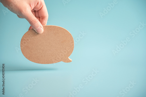 Talk bubble speech icon. Hand holding blank empty bubbles design elements on blue background. Chat on line symbol. copy space.