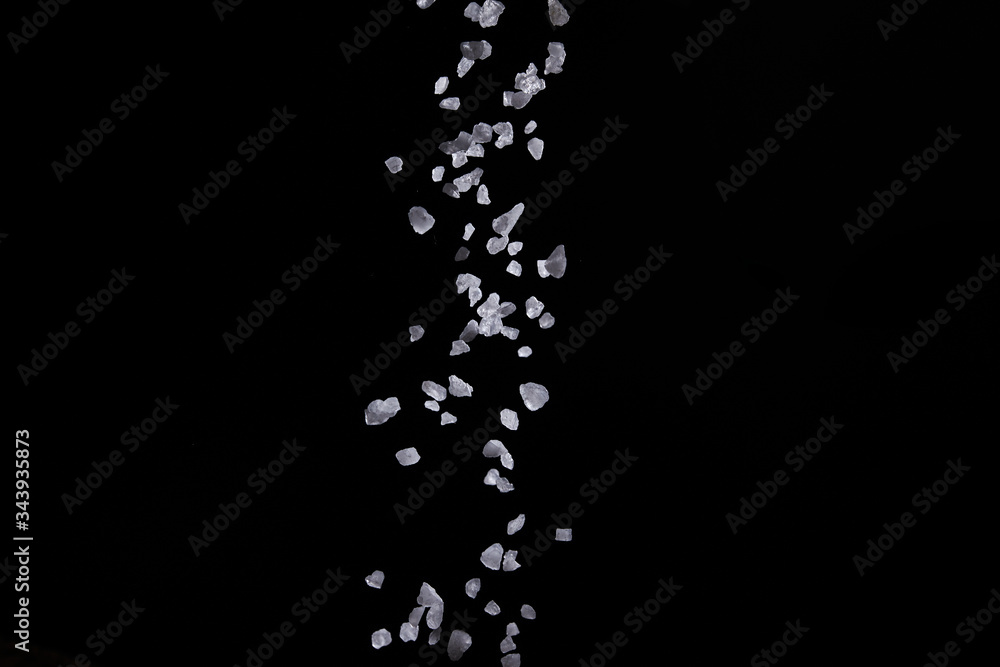 Obraz premium Sprinkle salt for seasoning On a black background