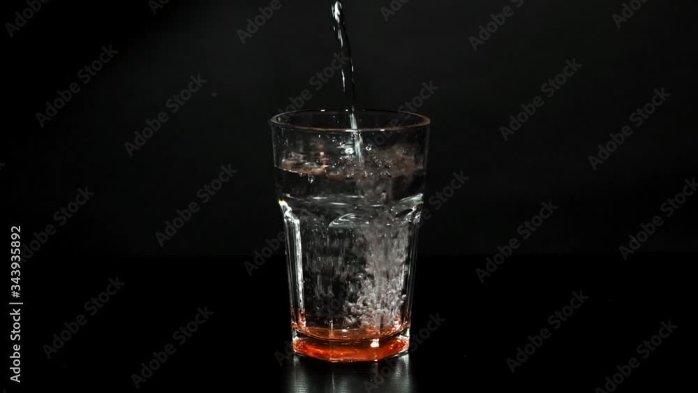 Pour clear clear water into a glass with splashes and bubbles on a black background. Healthy lifestyle. Drinking water. Pour clear clear water into a glass with splashes and bubbles on a black background. Healthy lifestyle. Drinking water.