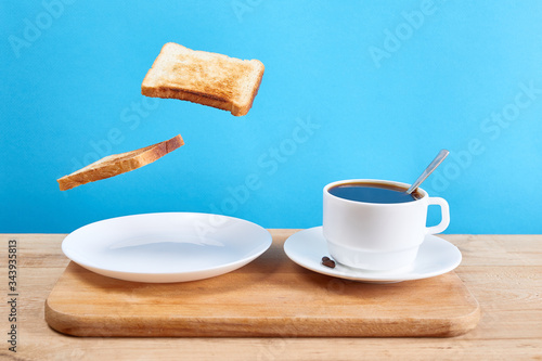 Fresh traditional breakfast with crispy toasts and cup coffee or tea on blue background. Levitation food concept.