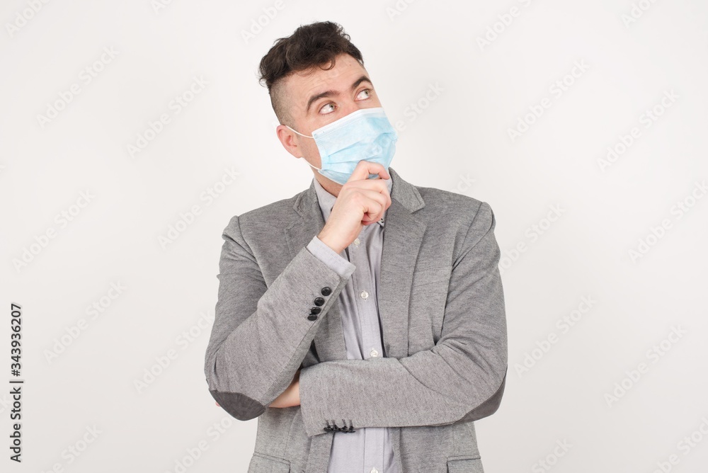Face expressions and emotions. Thoughtful young man in casual clothes holding hand under his head, having doubtful look. Face expressions and emotions. Thoughtful young man in casual clothes holding hand under his head, having doubtful look.